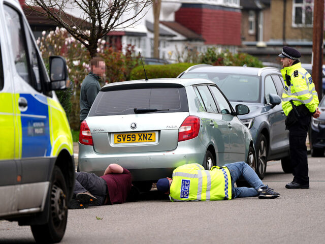 FACES PIXELATED BY PA PICTURE DESK Police checking the engine and undercarriage of a teal-