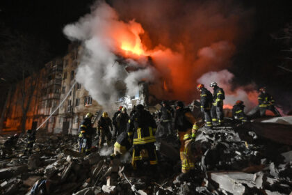 Firefighters extinguish a blaze and clear rubble at a five-story residential building in K