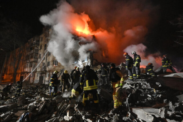 Firefighters extinguish a blaze and clear rubble at a five-story residential building in K