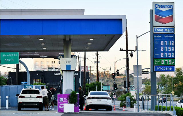 The sign of a Chevron gas station displays current prices as drivers pump gas in Rosemead,