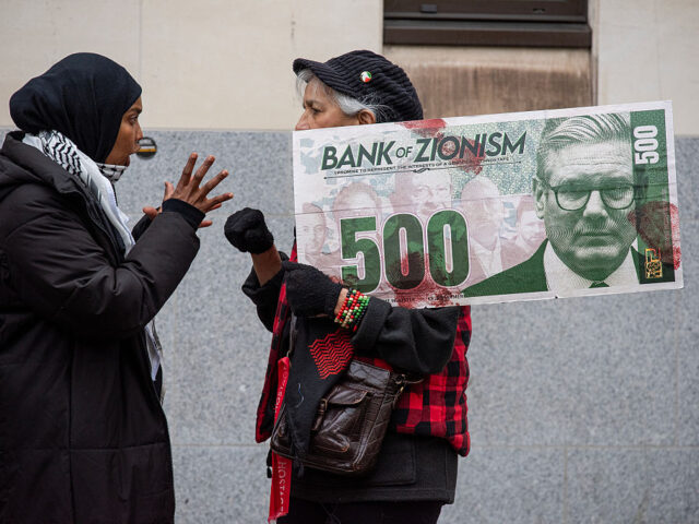 A protester holds a large fake bank note with the photo of LONDON, UNITED KINGDOM - 2026/03/27: A protester holds a large fake bank note with the pho