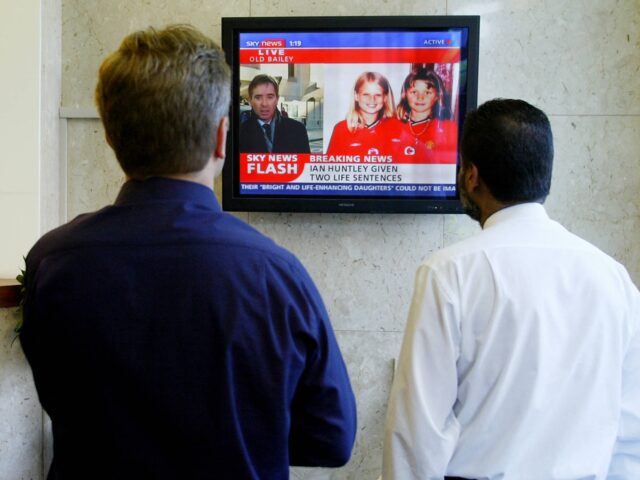 Two men watch a TV monitor as Ian Huntley is sentenced to two life terms in prison for mur