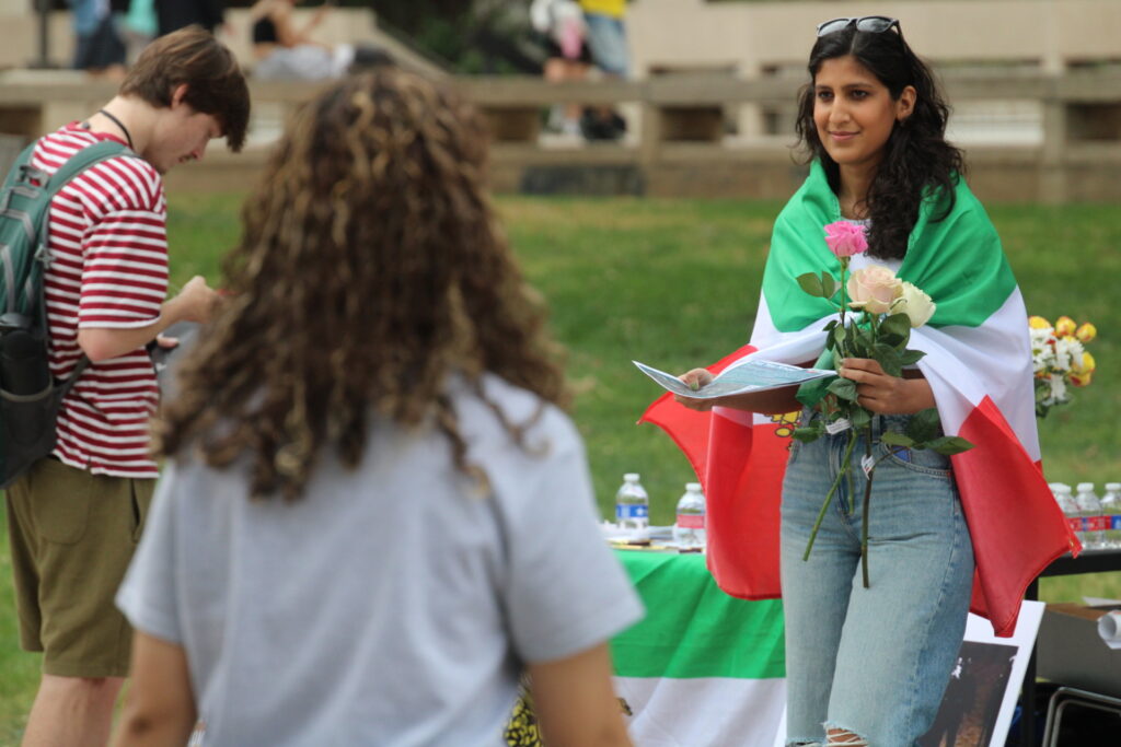 Uno studente iraniano saluta i passanti con informazioni sull'Iran e fiori a sostegno dell'operazione Epic Fury (Randy Clark/Breitbart Texas)