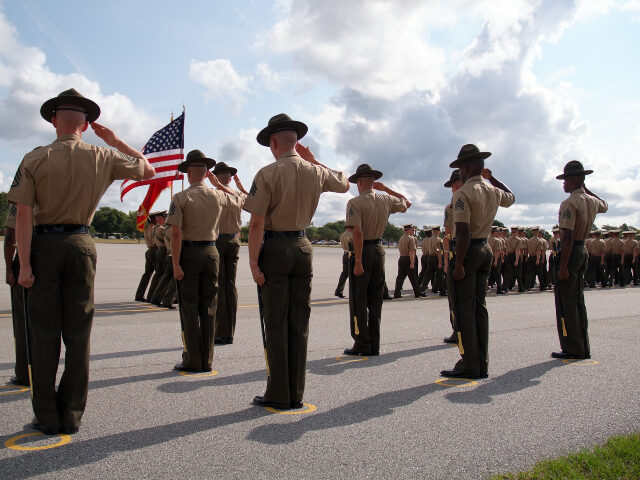 Dramatic shot of Drill Instructors saluting the U.S. flag during the graduation of recruit