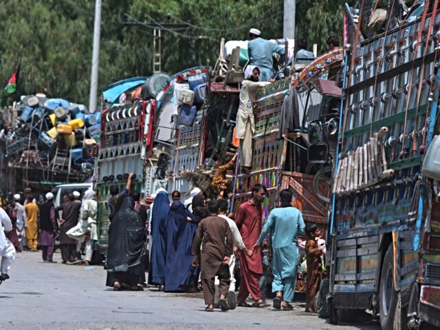 FILE - Afghan refugee families heading back to their homeland, gather next to trucks loade