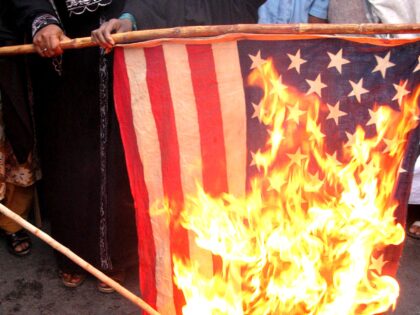 Female supporters of an Islamic party burn an American flag during a protest rally against