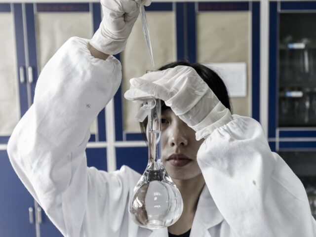 A technician holds a beaker in a quality control laboratory at a China Grand Pharmaceutica