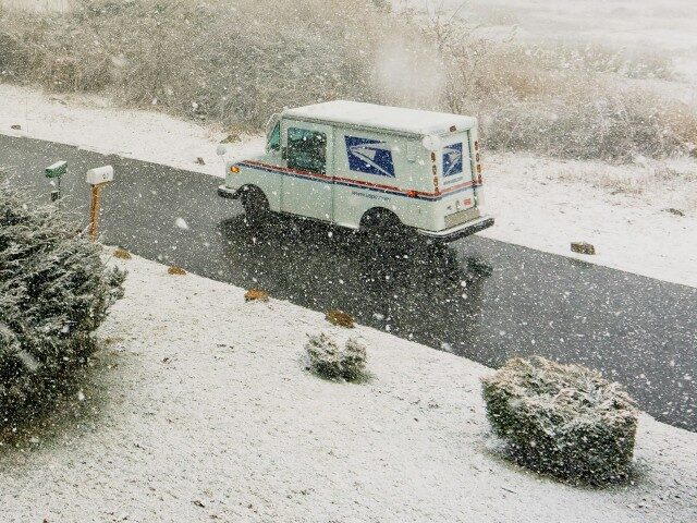 a white Postal Service truck driving down a snow covered road