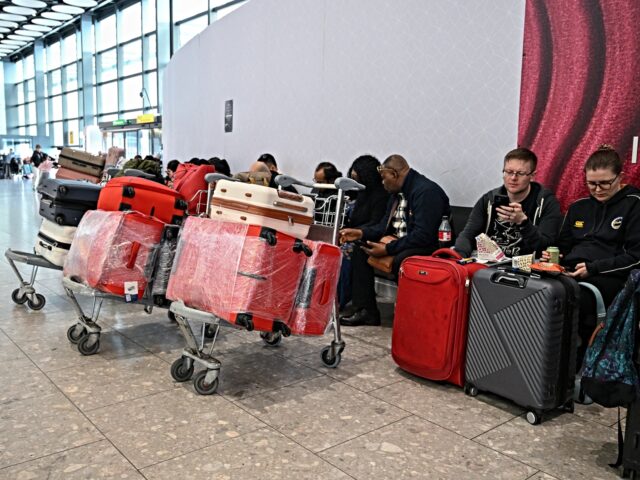 Passengers sit waiting for news about flights at Terminal 4 at London Heathrow Airport in