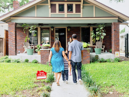 A family meeting with a real estate agent in front of the house on sale - stock photo