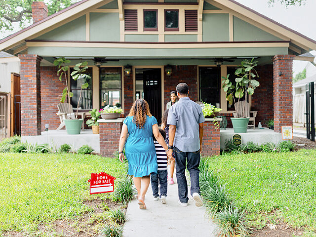 A family meeting with a real estate agent in front of the house on sale - stock photo