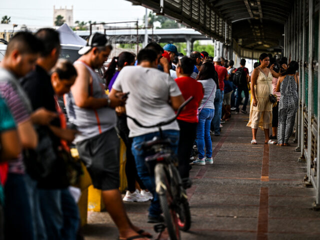 Migrants mostly form Central America wait in line to cross the border at the Gateway Inter