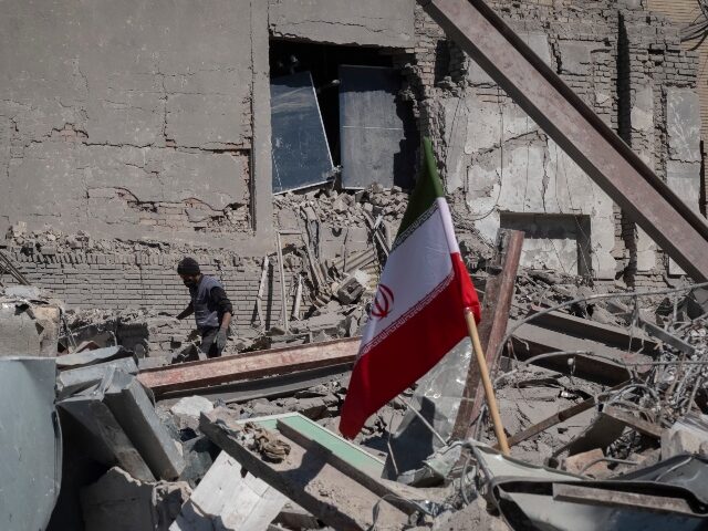 iran-rubble-flag-getty An unidentified man works among the ruins of a police station that is struck during U.S.-I