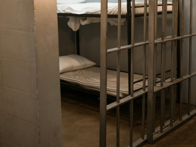 A Bunk Bed With Striped Linen Behind Bars