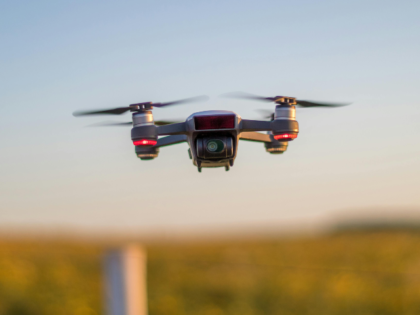 Drone recording video while flying above autumn trees in countryside