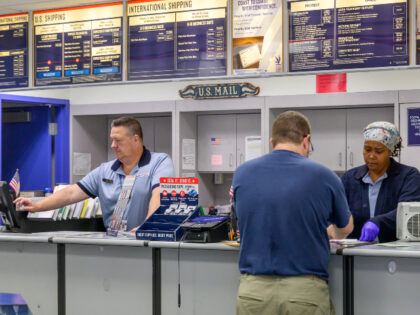 Postal workers Bill Wiltse and Michelle Byron wait on a customer, Mike, in the Latham Post