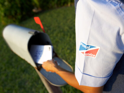 postal worker delivers mail to mailbox at home