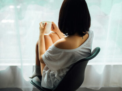 unhappy young woman sitting at window