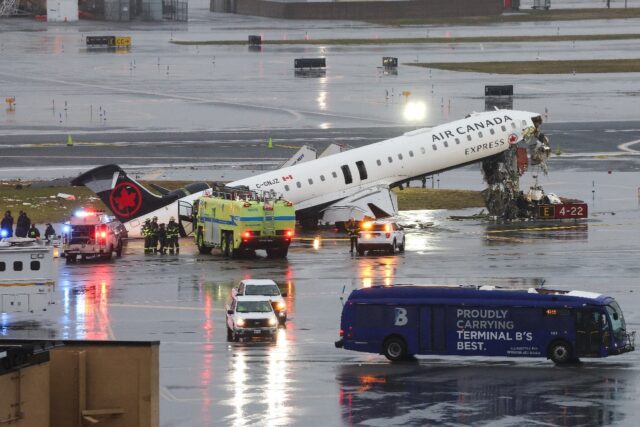 An Air Canada Express CRJ-900 sits on the runway after colliding with a Port Authority fir