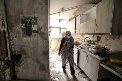 An Iranian woman walks through the destroyed kitchen in a home following a military strike