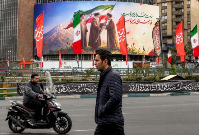 A billboard showing Mojtaba Khamenei receiving the national flag from his father, watched