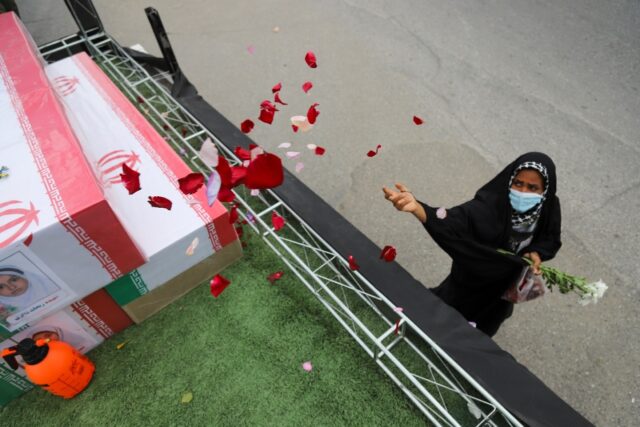 In this handout picture from Iranian state media, a mourner tosses flower petals on the co