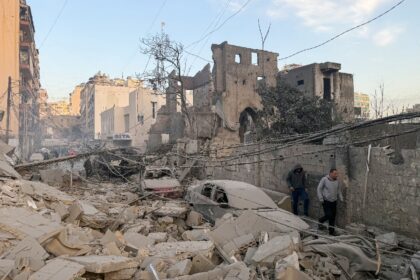 People walk past rubble at the site of an Israeli air strike in Beirut's Bashoura nei