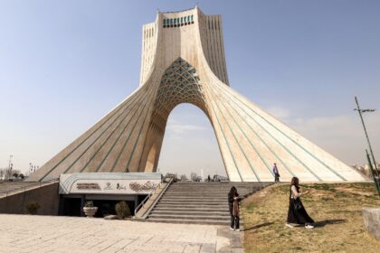 People walk near Tehran's landmark Azadi (Freedom) Tower in February before the Unite