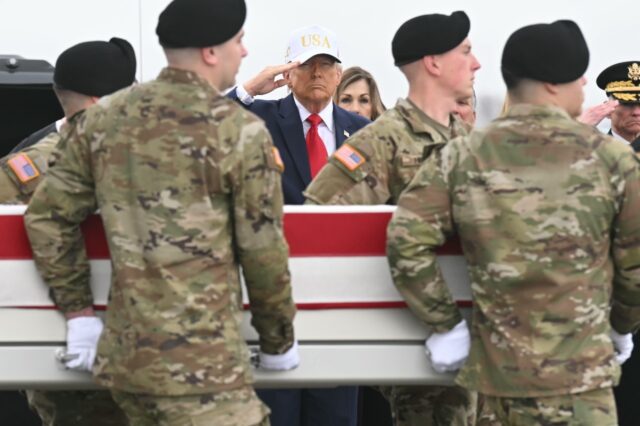 President Donald Trump salutes as members of an Army team carry a case containing the rema