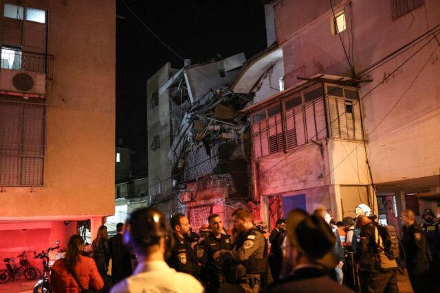 Security forces and first responders gather next to a damaged building at a site struck by
