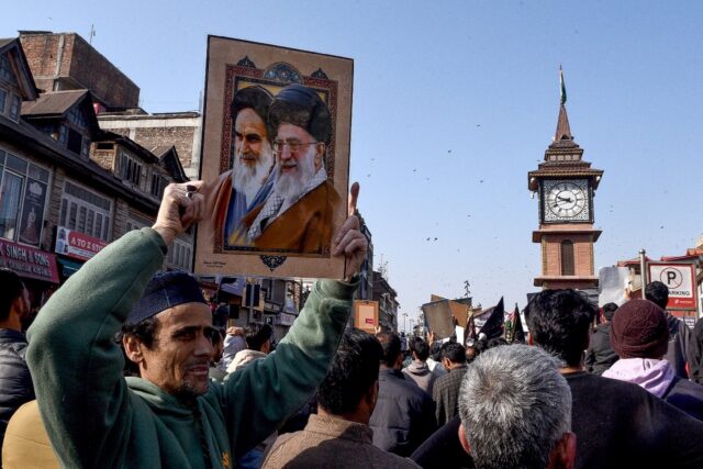 A Shiite Muslim holds a photograph of Iran supreme leader Ayatollah Ali Khamenei (R) and f