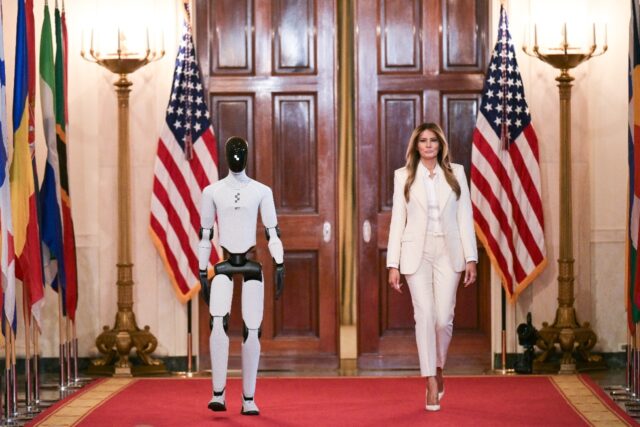 US First Lady Melania Trump walks with a humanoid robot as she arrives for the Fostering t