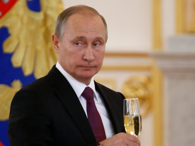 Russian President Vladimir Putin holds a glass during a ceremony of receiving diplomatic c