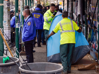 FILE — Sanitation workers move a tent to a garbage truck at a small homeless encampment