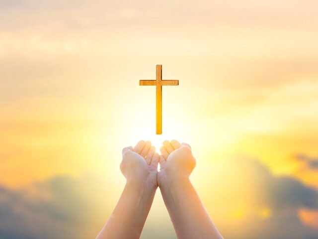 Religion Christ and the cross of Jesus Christ at sunset, golden light.