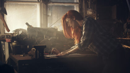 Redhead woman working with tools. Repairing car engine