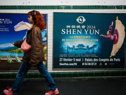 This photograph taken on March 1, 2024, shows a woman walking past posters of the Shen Yun