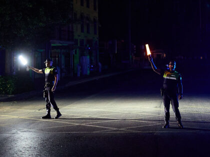Two police officers direct traffic with flashlights during the power outage that affects S