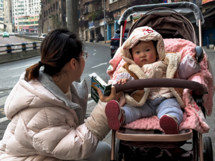 CHONGQING, CHINA - JANUARY 09: A woman crouches beside a baby sitting in a stroller on a s