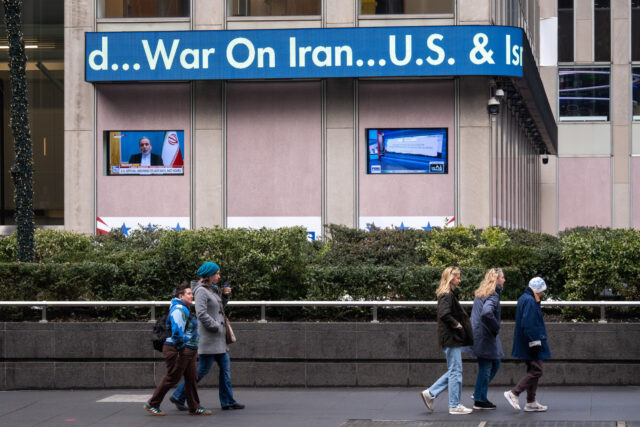 Trump Starts Massive Strikes, Urging Iranians To Seize Power A news ticker displays news about US strikes on Iran on the News Corp. building in New Yor