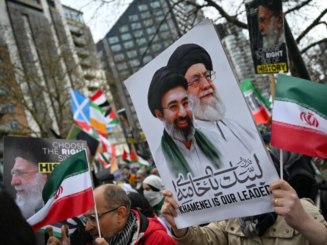 A protester holds a placard with an image of late Ayatollah Ali Khamenei (centre R) and Ir