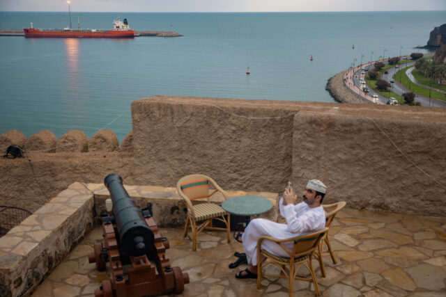 MUSCAT, OMAN - MARCH 25: Locals take photos of two bulk carriers anchored at Muscat Ancho