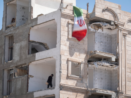 An Iranian volunteer works on a building damaged during military operations in a residenti