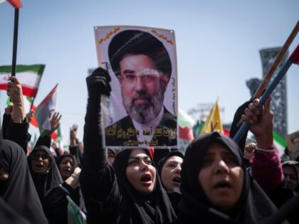 A veiled Iranian demonstrator holds a portrait of Iran's Supreme Leader Ayatollah Mojtaba