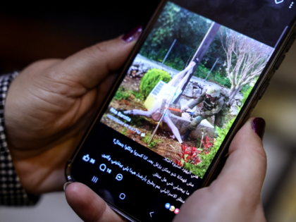 TOPSHOT - A woman checks a social media post on her mobile phone featuring an image that a