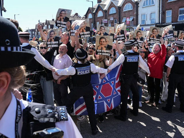 Police hold back protesters holding placards as a car (not pictured) carrying Britain'