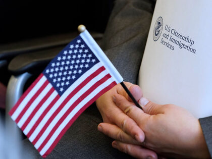 An applicant holds an American flag and a packet while waiting to take the oath to become