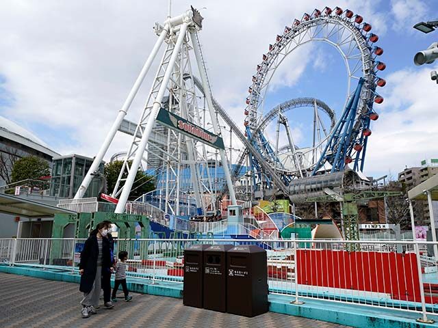 People wearing protective masks walk past the Tokyo Dome City Attractions entertainment co