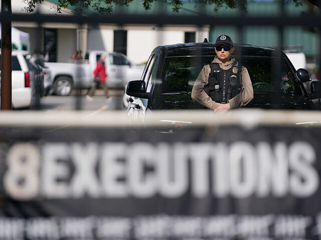 A member of law enforcement stands near a vehicle at the department of corrections before