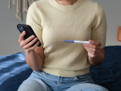 Woman with pregnancy test and phone